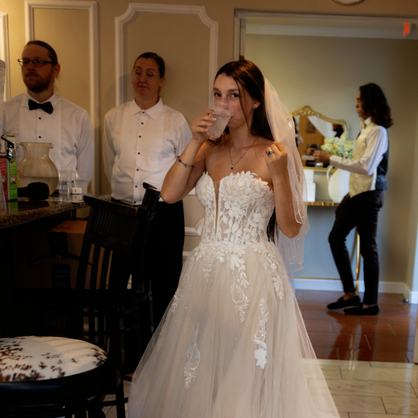 bride drinking water in front of wait staff in bar area