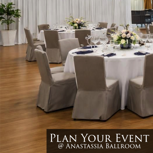 beige padded chairs navy blue napkins, white banquet tables, floral rose centerpieces against white curtain wall